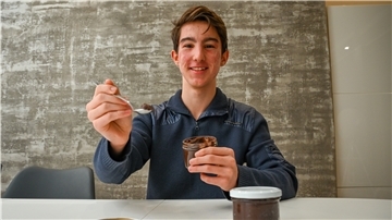 Ein Junge hält eine Schokoladencreme in der Hand.