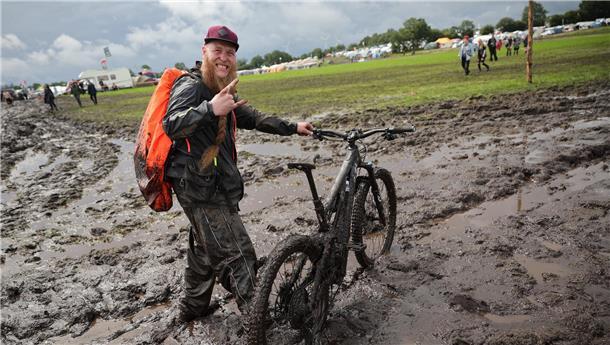 Ein Mann schiebt sein Mountainbike durch den Matsch. 