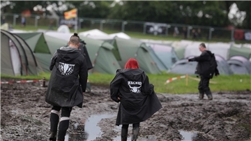 Metal-Fans sind auf dem schlammigen Festivalgelände unterwegs.