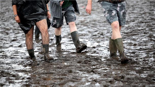 Metal-Fans sind auf dem schlammigen Festivalgelände unterwegs.