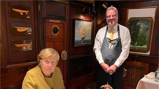 Michael Besch hat Angela Merkel das Gästebuch des Fischereihafen-Restaurants gereicht, damit sie sich darin verewigt.