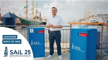 Ein Mann in Jeans und weißem Hemd steht an einem Hafenbecken. 