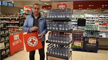 Michael Lewin steht an einem Aufsteller im Supermarkt (Rewe, Nordholz) mit Wasserflaschen.