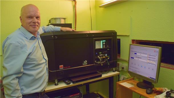 Ein Mann mit Hemd steht in einem Kino-Vorführraum neben dem Projektor.