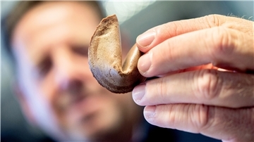 Eine Hand hält einen Glückskeks hoch. 