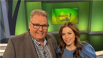 Ein Mann  und eine Frau stehen in einem Fernseh-Studio.
