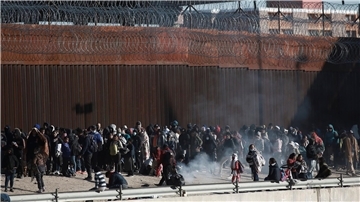 Migranten aus Lateinamerika stehen an der Grenzmauer zwischen Mexiko und den USA.