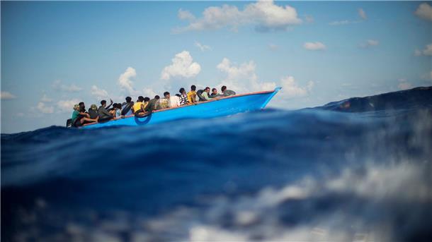 Migranten sitzen in einem Holzboot südlich der italienischen Insel Lampedusa auf dem Mittelmeer.