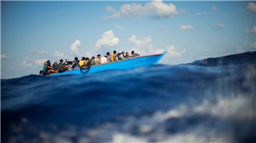 Migranten sitzen in einem Holzboot südlich der italienischen Insel Lampedusa auf dem Mittelmeer.