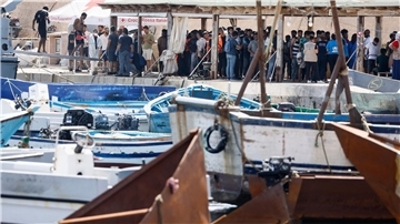 Migranten stehen an einem Hafen auf Lampedusa.