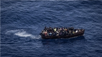 Migranten steuern ein Boot in Richtung der Insel Lampedusa.