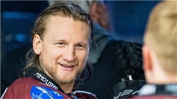 Mann mit langen Haaren lächelt.