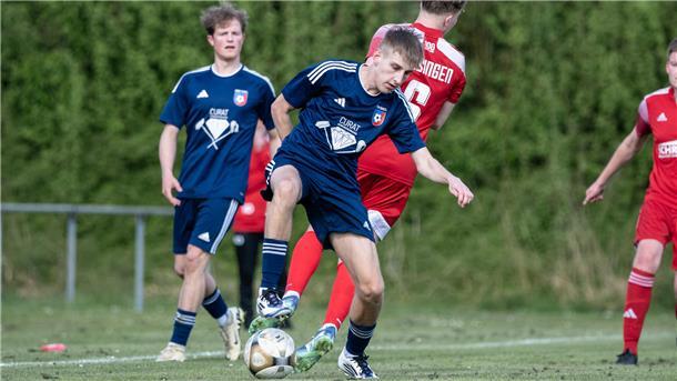 Ein Mann im Sporttrikot hat einen Ball am Fuß.