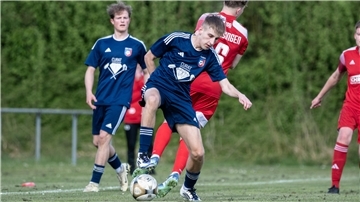 Ein Mann im Sporttrikot hat einen Ball am Fuß.