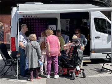 Frauen und Männer stehen vor einem Kleinbus.