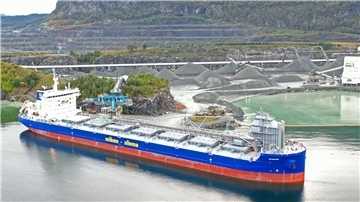 Selbstentladeschiff der Mibau Stema Group beim Beladen in einem norwegischen Steinbruchhafen; im Hintergrund große Gesteinshalden und Förderanlagen.