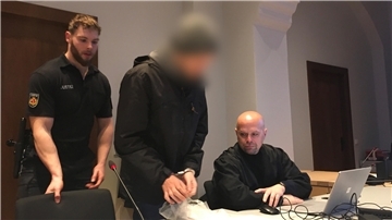 Mann mit Handschellen neben einem Justizbeamten