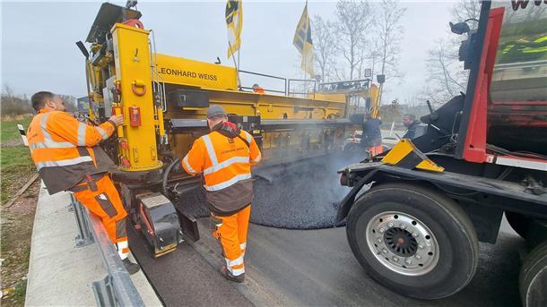 Mit einer Asphalt-Bohle wird der heiße Asphalt aus dem Kocher auf dem Untergrund verteilt. 