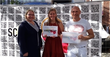Maike Agit (links), Schulleiterin der Oberschule Schiffdorf, und ihre beiden Kulturkoordinatoren, Claudia Helm (Mitte) und Bernd Gerdes, halten die Tafel hoch, die ihre Schule nun als Kulturschule auszeichnet.