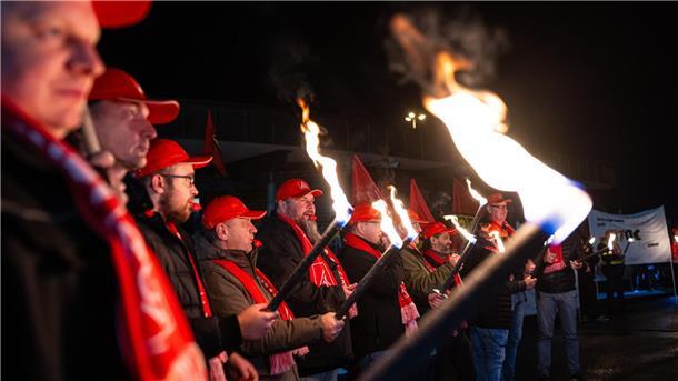 Warnstreiks an zahlreichen Werkstoren in Niedersachsen Mit Fackeln stehen Mitarbeiter von Volkswagen vor dem Volkswagen-Werk.