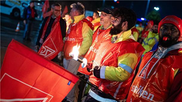 Warnstreiks an zahlreichen Werkstoren in Niedersachsen Mit Fackeln stehen Mitarbeiter vor dem Betriebsgelände der Clarios Varta Hannover GmbH.