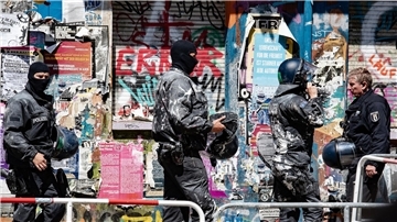 Mit Farbe beworfene Polizeibeamte verlassen das Haus Nr. 94 in der Rigaer Straße in Berlin.