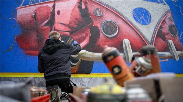Mit Farben aus Sprühdosen sprayt Mathias Oppen ein Kunstwerk an eine Wand. 