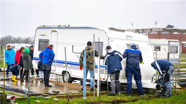 Campingsaison an der Küste startet: Camper stehen Schlange Mit gegenseitiger Unterstützung schieben die Urlauber ihre Wohnwagen auf die Parzellen.