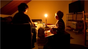 Eine Mutter sitzt mit ihrem Sohn in ihrer abgedunkelten Wohnung