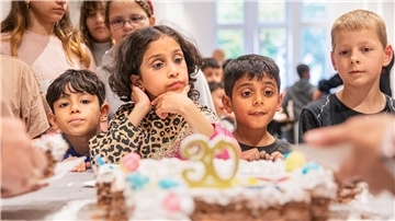 Kinder stehen vor einer Torte.