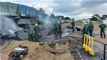 Mit Hochdruckreinigern und in Schutzkleidung reinigen Kursteilnehmer eine Felsformation von Öl. Im Trainingszentrum im französischen Brest können sie mit echtem Öl üben.