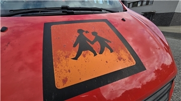 Die Front eines roten Kleinbusses mit einem orangefarbenen Schulbusschild