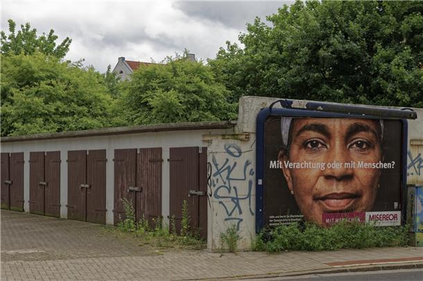 "Mit Verachtung oder mit Menschen?" Ein Plakat von Misereor an einem Garagenhof in Lehe, das sinnbildlich für das Kernthema im Blog von Fotograf Thomas Damson steht.