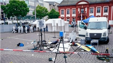 Mitarbeiter der Spurensicherung stehen auf dem Marktplatz hinter einem zertrümmerten Stand.