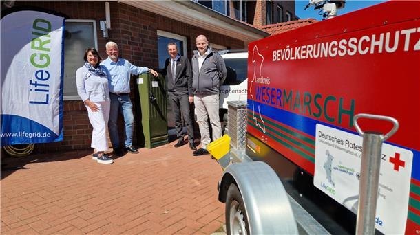 Eine Frau und drei Männer stehen vor einem Seniorenheim in Ovelgönne (Landkreis Wesermarsch). Im Vordergrund ist ein Anhänger des Bevölkerungsschutzes zu sehen.