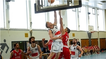 Basketballer kämpfen unter dem Korb um den Ball.