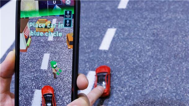 Spielwarenbranche will mit Neuheiten Kauflust schüren Mittels Smartphone, welches ein reales Spielzeugauto mit der Kamera erfasst, wird beim Spiel „Zombie Crasher AR“ von Augmented Robotics eine virtuelle Straßenszene dargestellt.