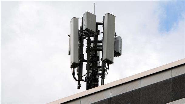Mobilfunkantennen des Funkstandards 4G (länglich) und 5G (quadratisch) sind auf einem Dach an einem kleinen Mast montiert.