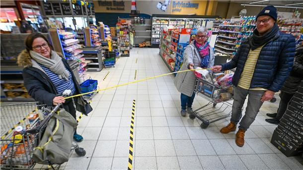 Monika Miesner (links) und Anja Neumann mit Thomas Gries zeigen im E-Center Roter Sand, was zwei Meter Abstand im Alltag im Supermarkt bedeuten.