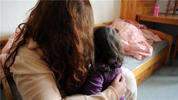 Frau umarmt ein Kind in einem Zimmer.
