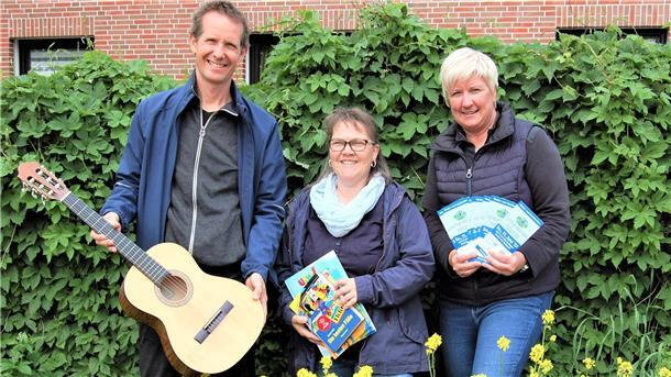 Musikschulleiter Pascal Gentner, Büchereileiterin Renate Schröter und Jugendpflegerin Martina Feldmann-Bienhoff werben vor einer grünen Hecke für die Veranstaltung "Little Motion" in Hagen