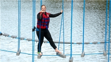 Eine Frau balanciert auf einem Kletterparkour