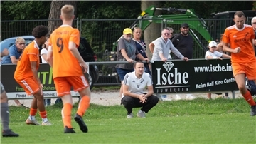 Ein Trainer hockt am Spielfeldrand. 
