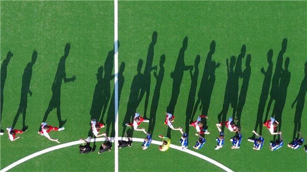 Fußballer werfen Schatten in der Sonne und klatschen sich auf dem Platz ab.