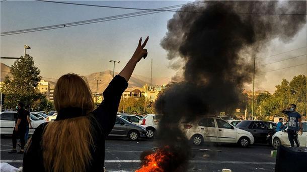 Politiker übernehmen Patenschaften für iranische Inhaftierte Nach dem Tod der 22-jährigen Mahsa Amini steht eine Frau während einer Demonstration in Teheran vor einem brennenden Autoreifen.
