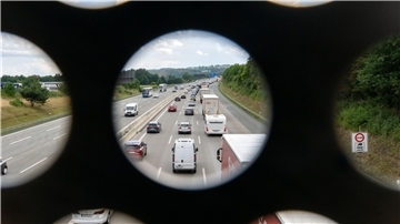  Zahlreiche Autos stehen auf der Autobahn im Stau, Aufnahme durch das Geländer einer Brücke