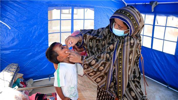Nach den schweren Überschwemmungen in Pakistan verabreicht eine Mitarbeiterin des Gesundheitswesen einem Kind eine Schluckimpfung gegen Polio.