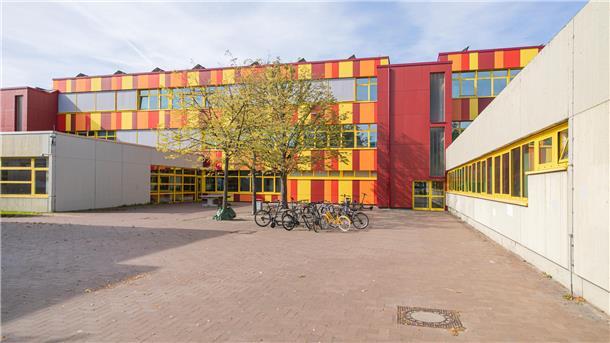Ein leerer Schulhof, in der Mitte stehen Fahrräder.