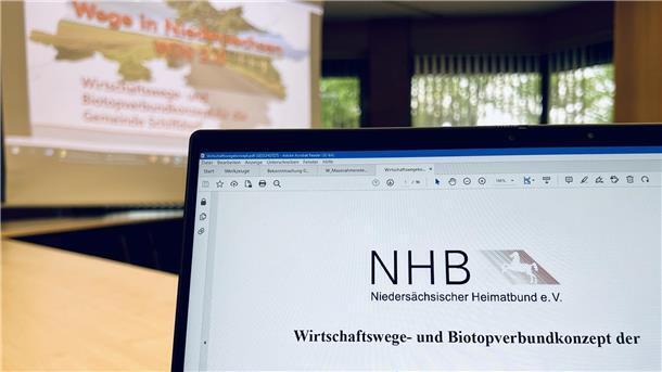 Laptop im Vordergrund, Präsentation im Hintergrund.