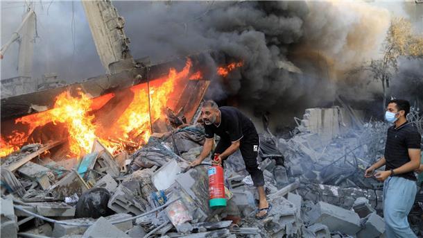 Nach einem israelischen Luftangriff in der Stadt Khan Yunes im südlichen Gazastreifen löschen Menschen das Feuer in den Trümmern.